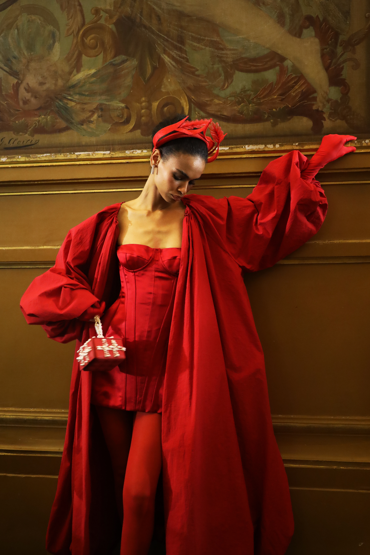 Model in red couture posed against a painted wall
