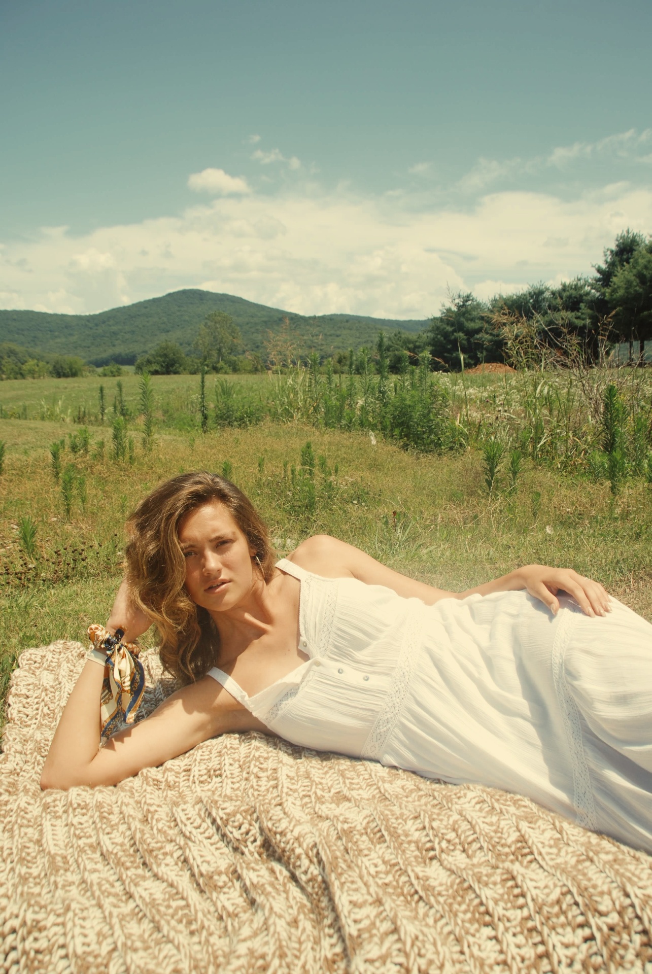 Model reclining on a woven blanket in soft summer light