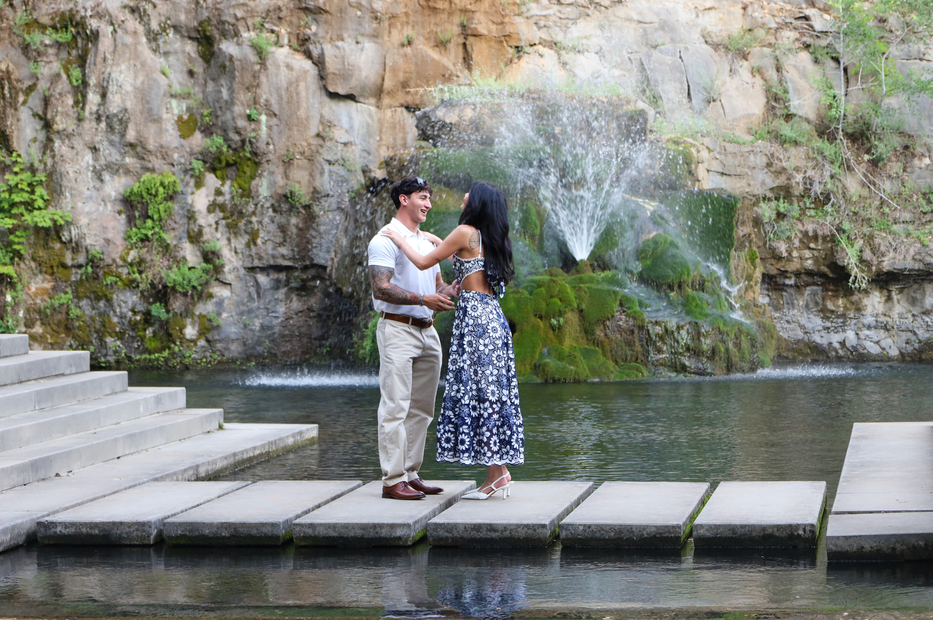 Couple embracing on stepping stones beside a waterfall