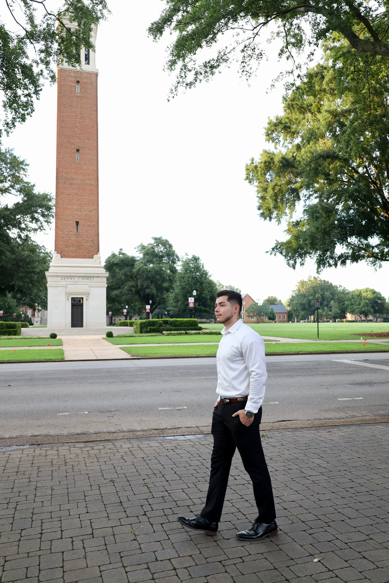 Graduate walking past Denny Chimes on the University of Alabama quad