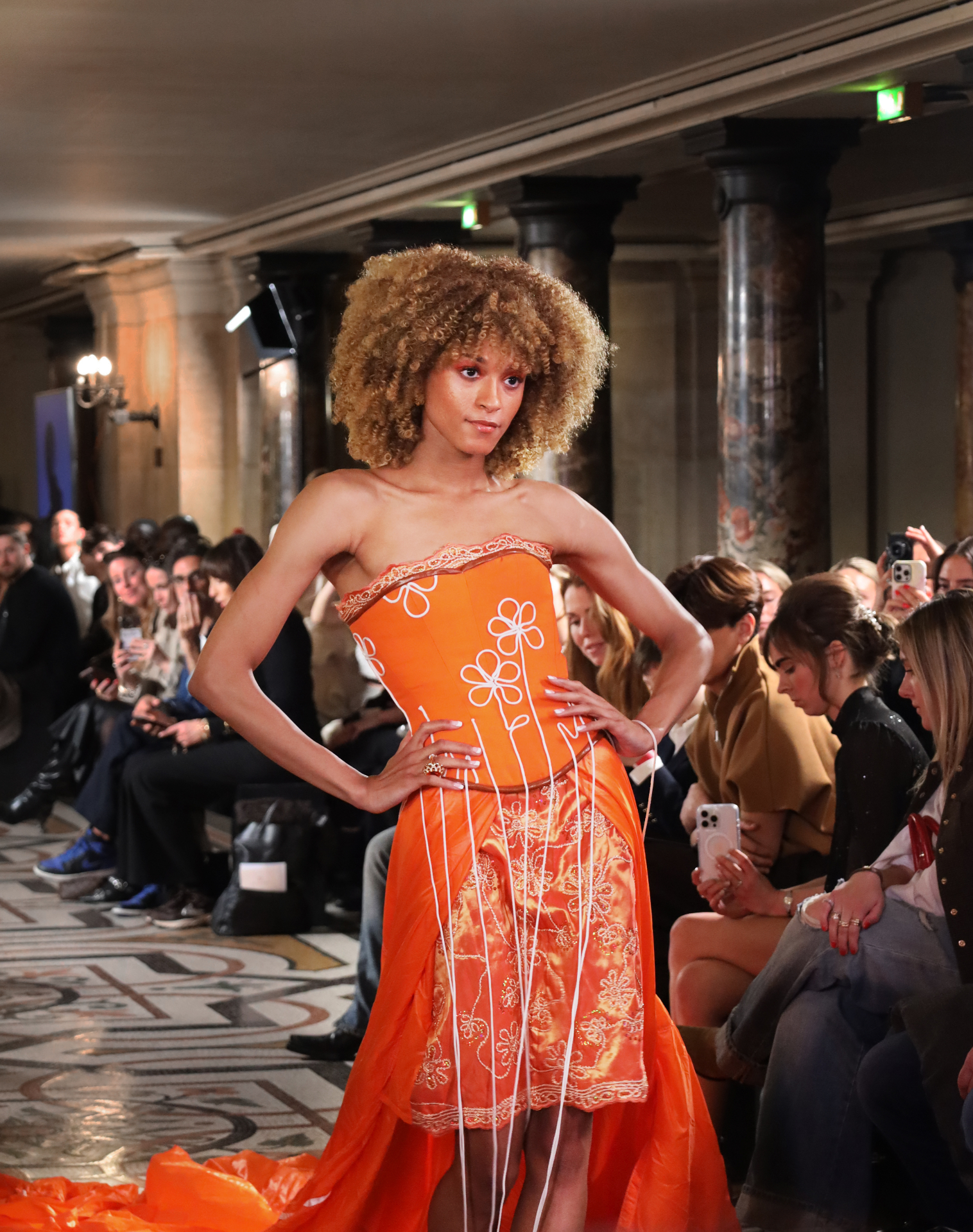 Model in orange floral corset on the runway