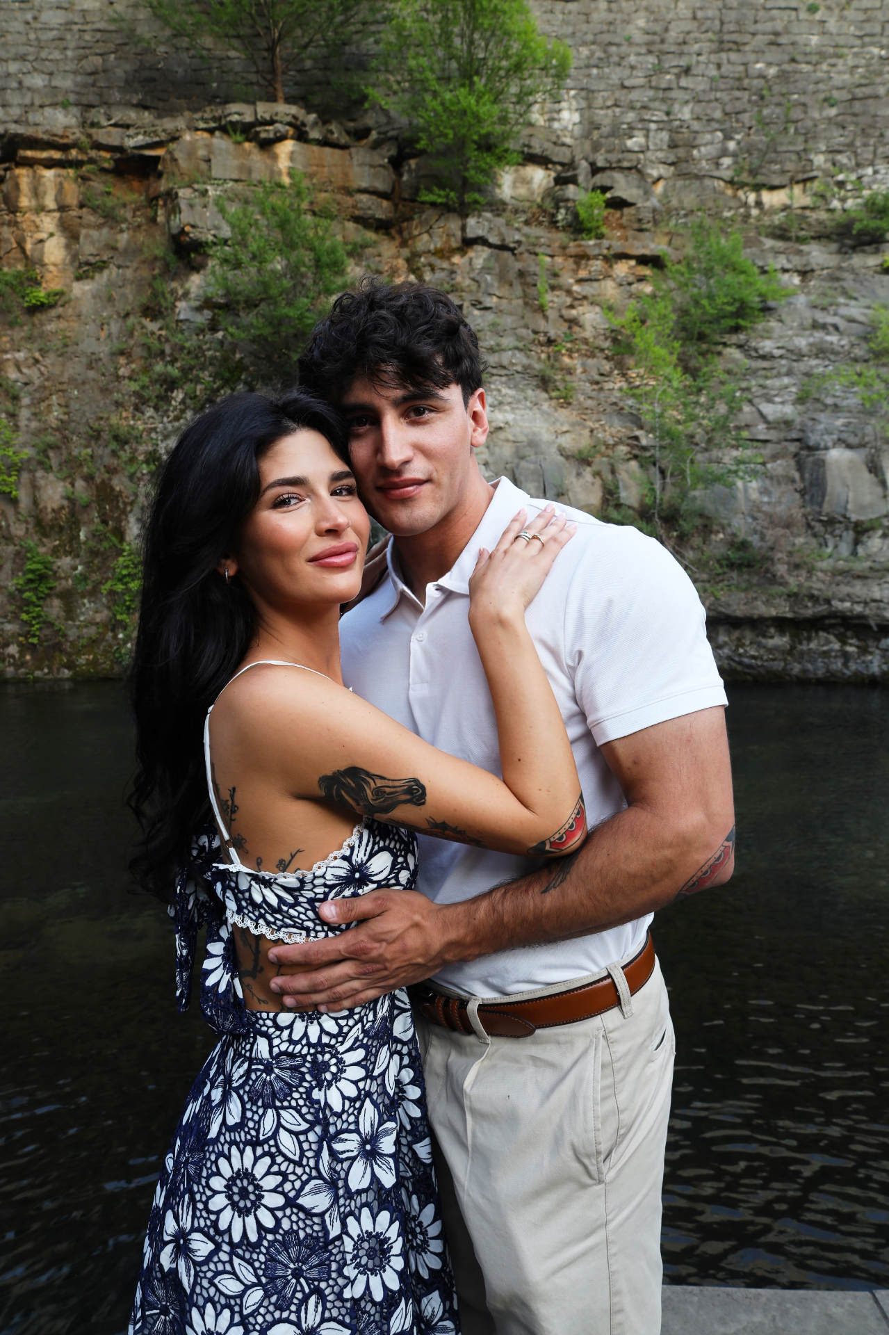 Engaged couple embracing in front of the quarry waterfall