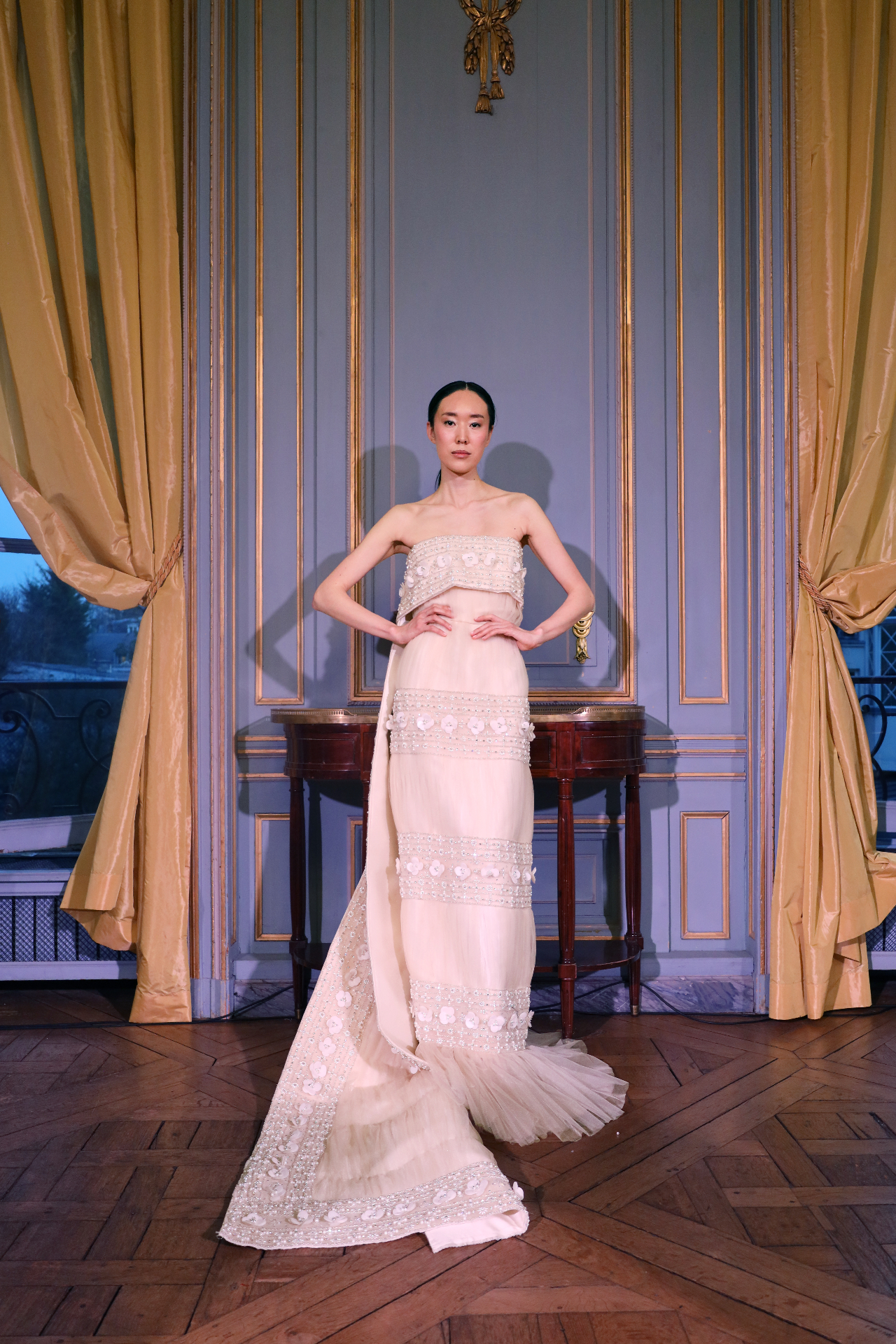 Ivory couture gown framed by blue-grey paneling and draped curtains