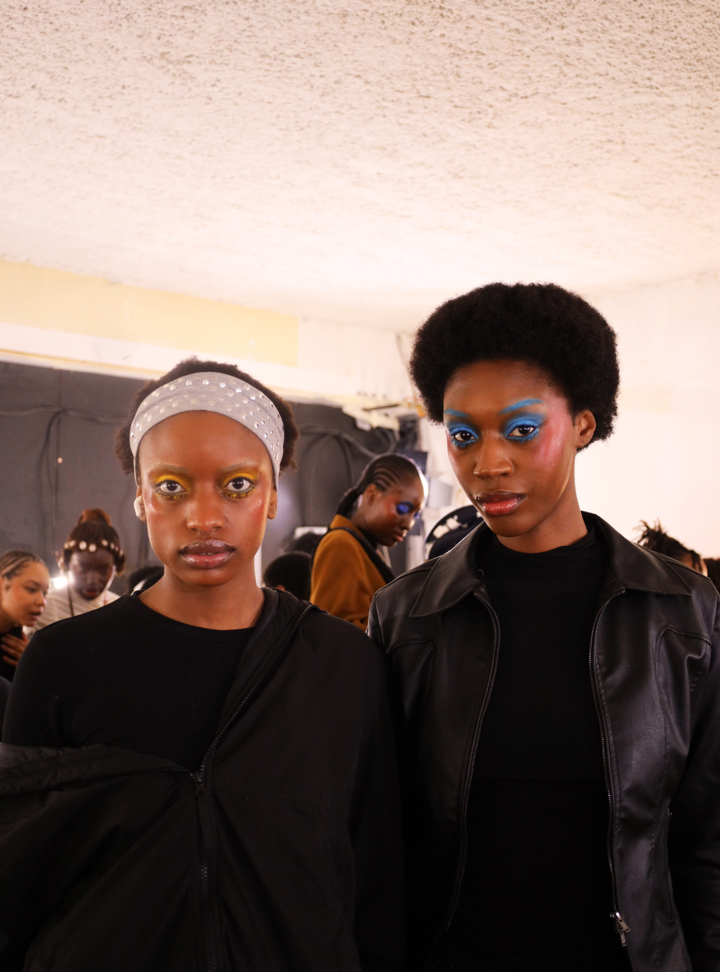 Two models backstage with bold editorial beauty looks