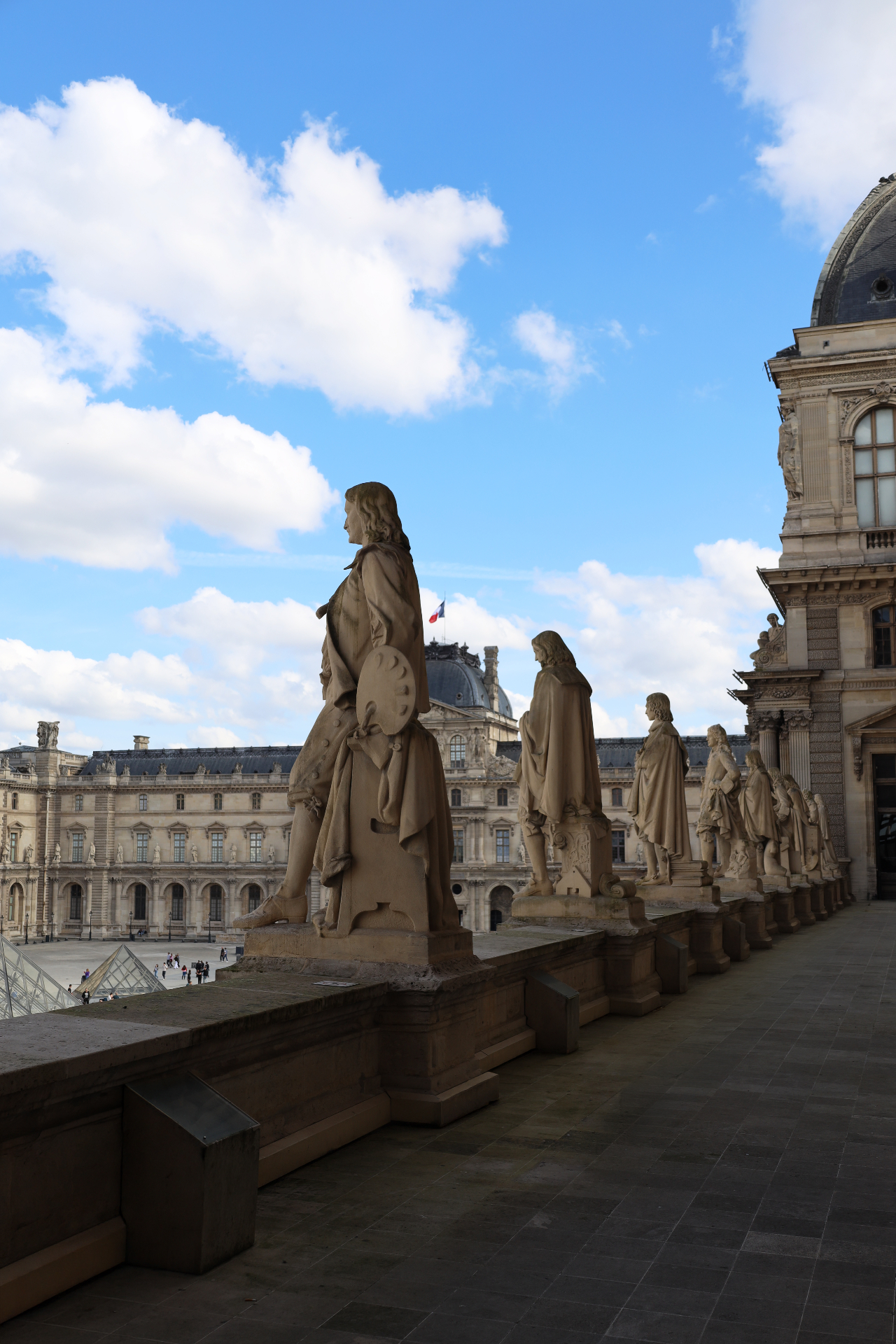 Statues of artists overlooking the Louvre courtyard from the rooftop