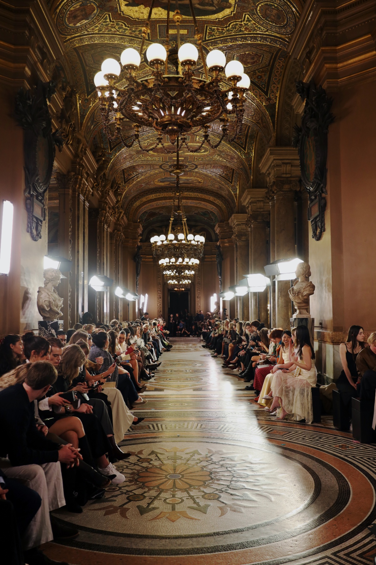 Gilded runway hall with chandeliers and audience