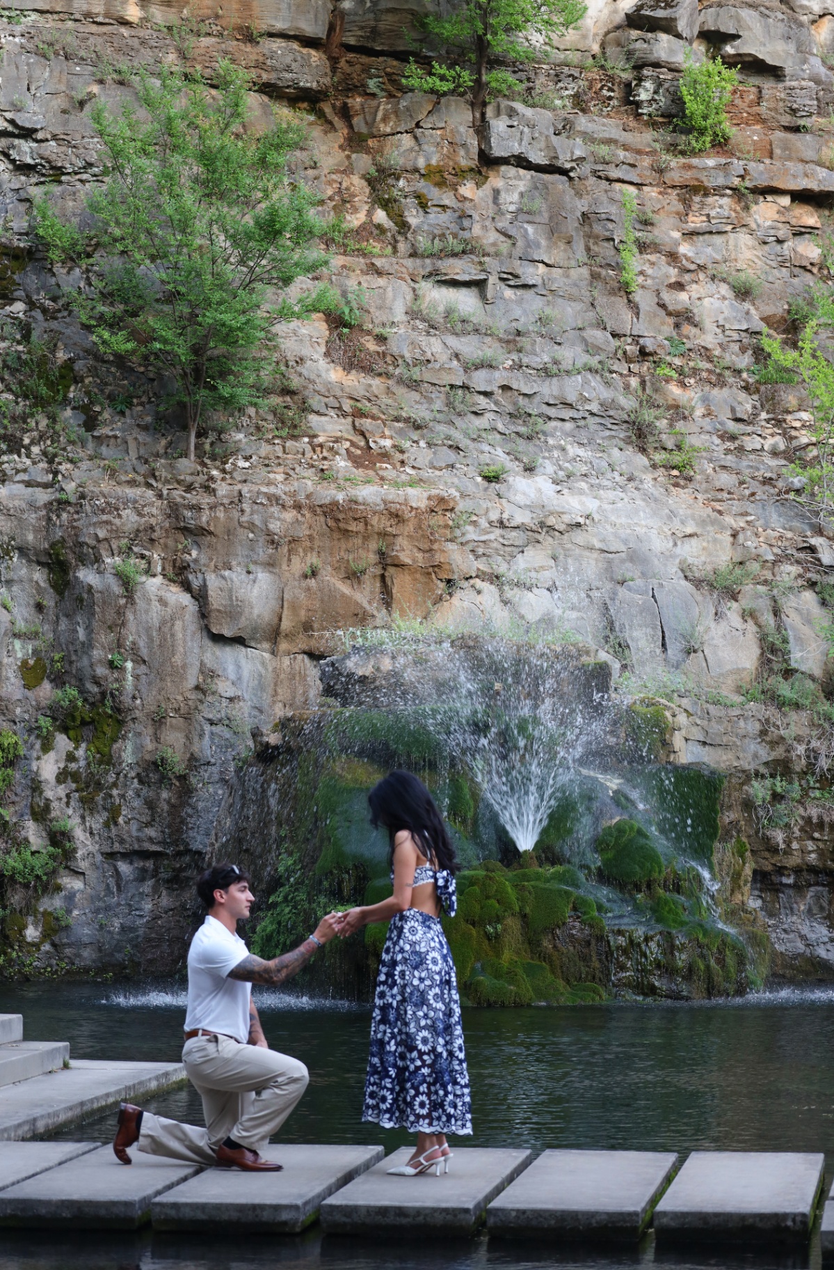 Proposal moment on stepping stones in front of a waterfall