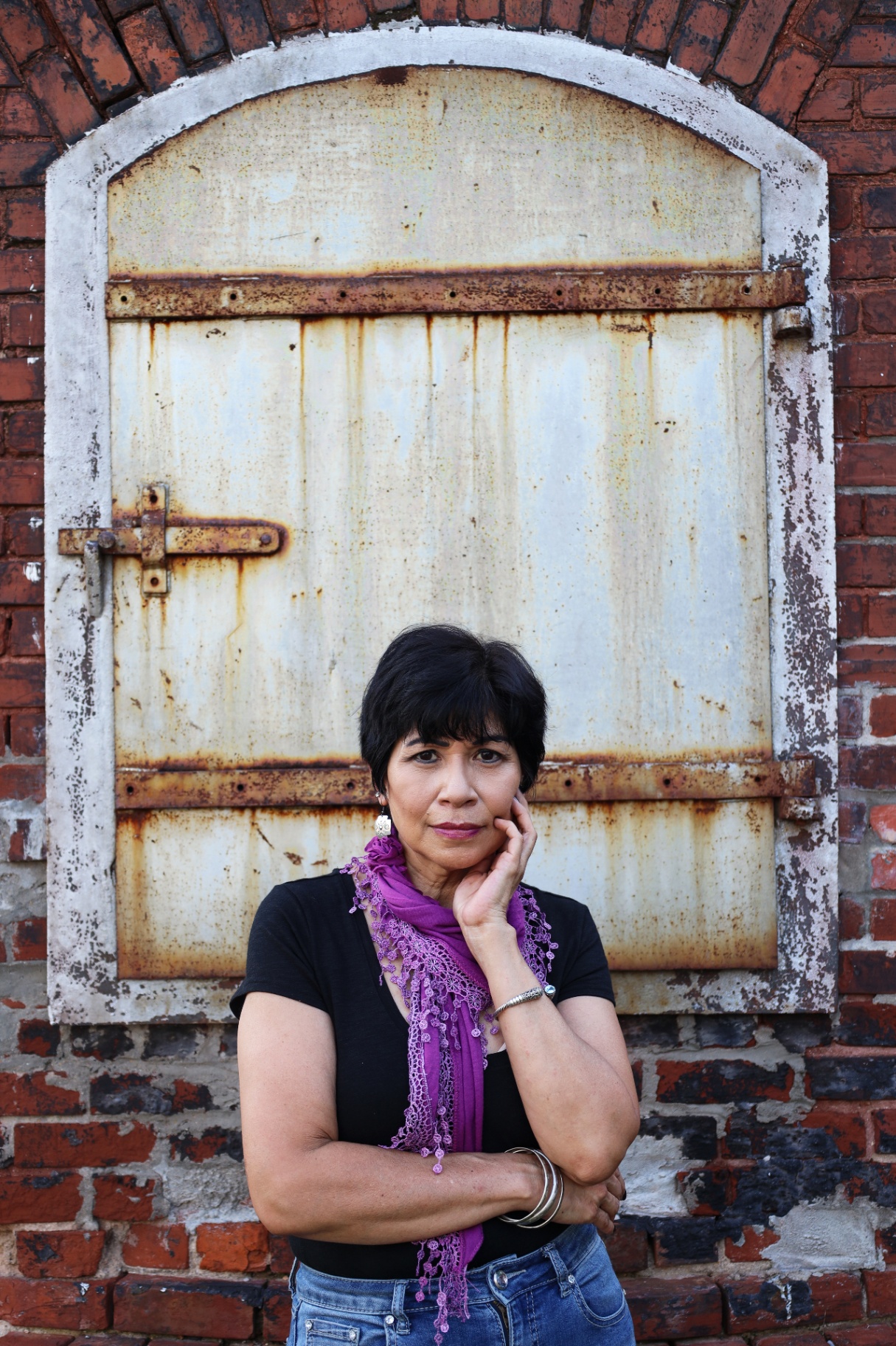 Portrait of a woman in front of a rustic iron door