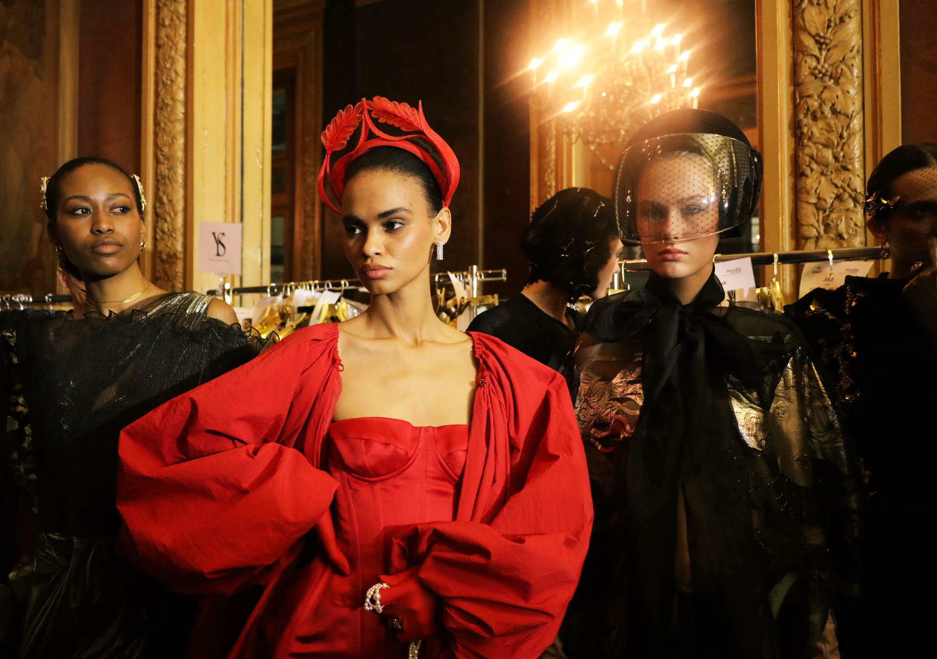 Backstage trio with red crown headpiece and veiled hat