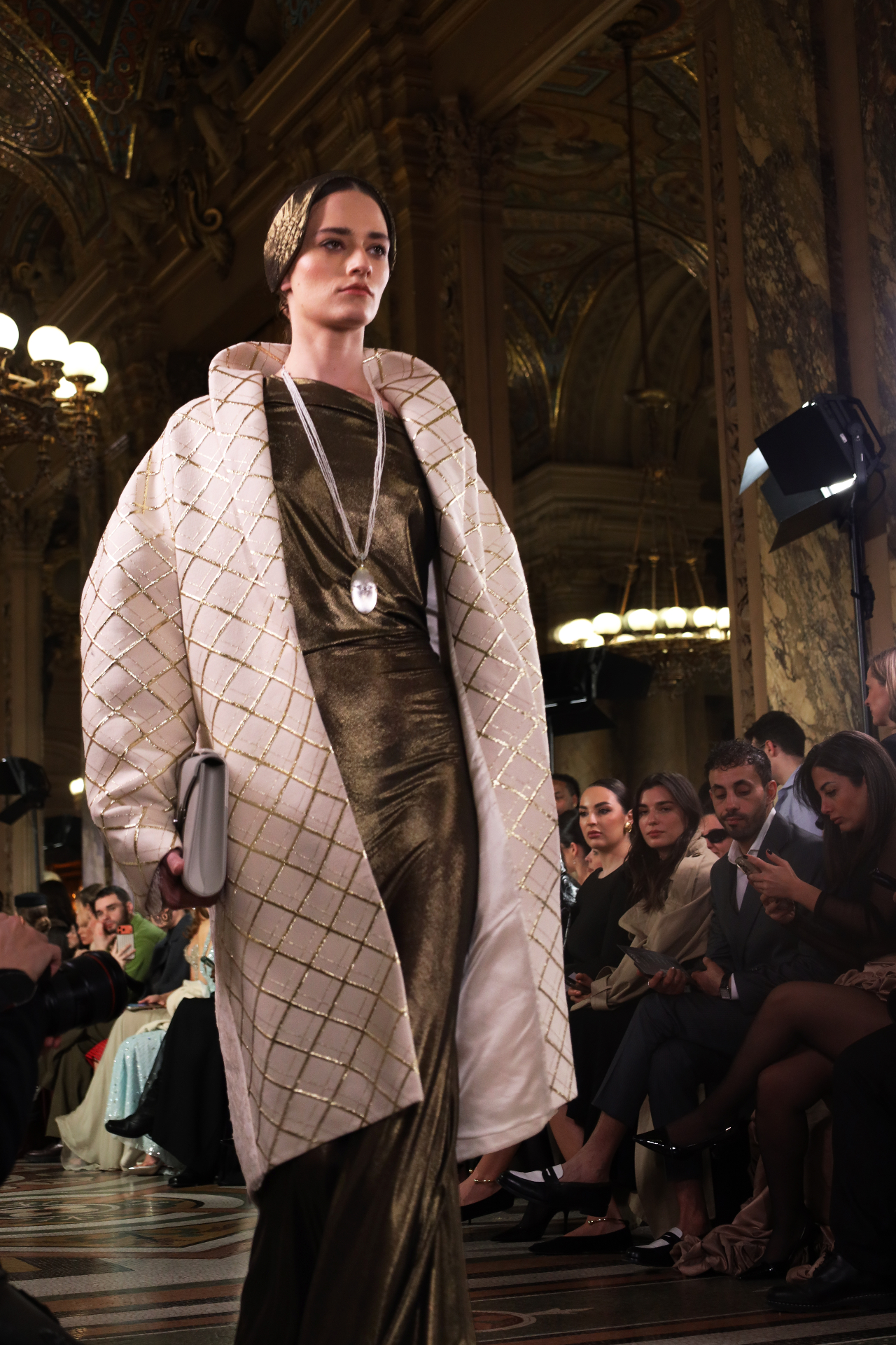 Model in gilded diamond-patterned coat on the runway