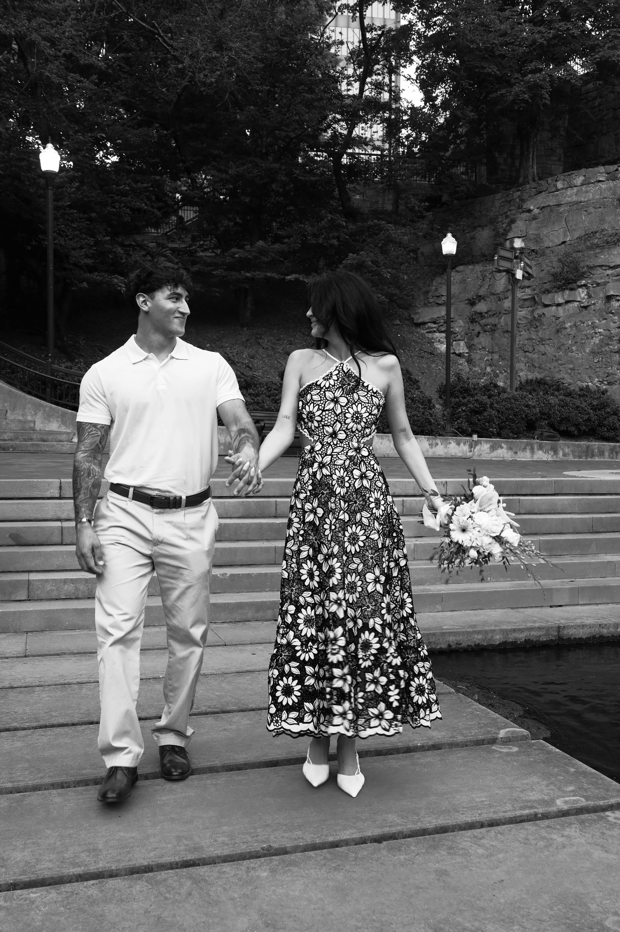 Black and white portrait of the couple walking hand in hand down stone steps