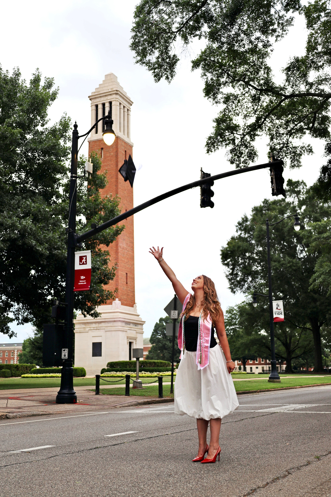 Graduate reaching toward Denny Chimes from the street