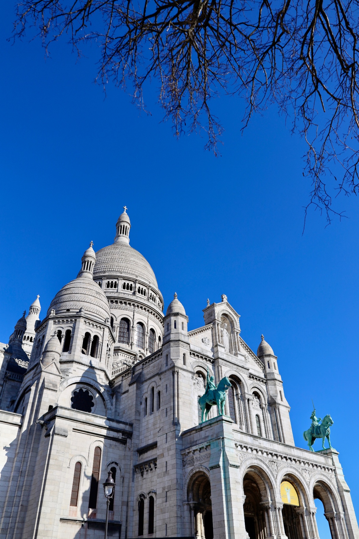 Sacré-Cœur Basilica framed by winter branches against a bright blue sky