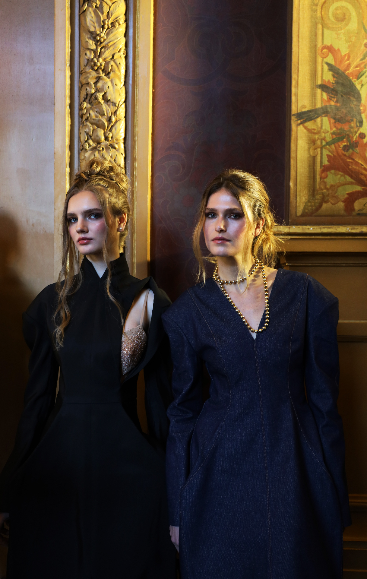 Two models against gilded baroque panels backstage