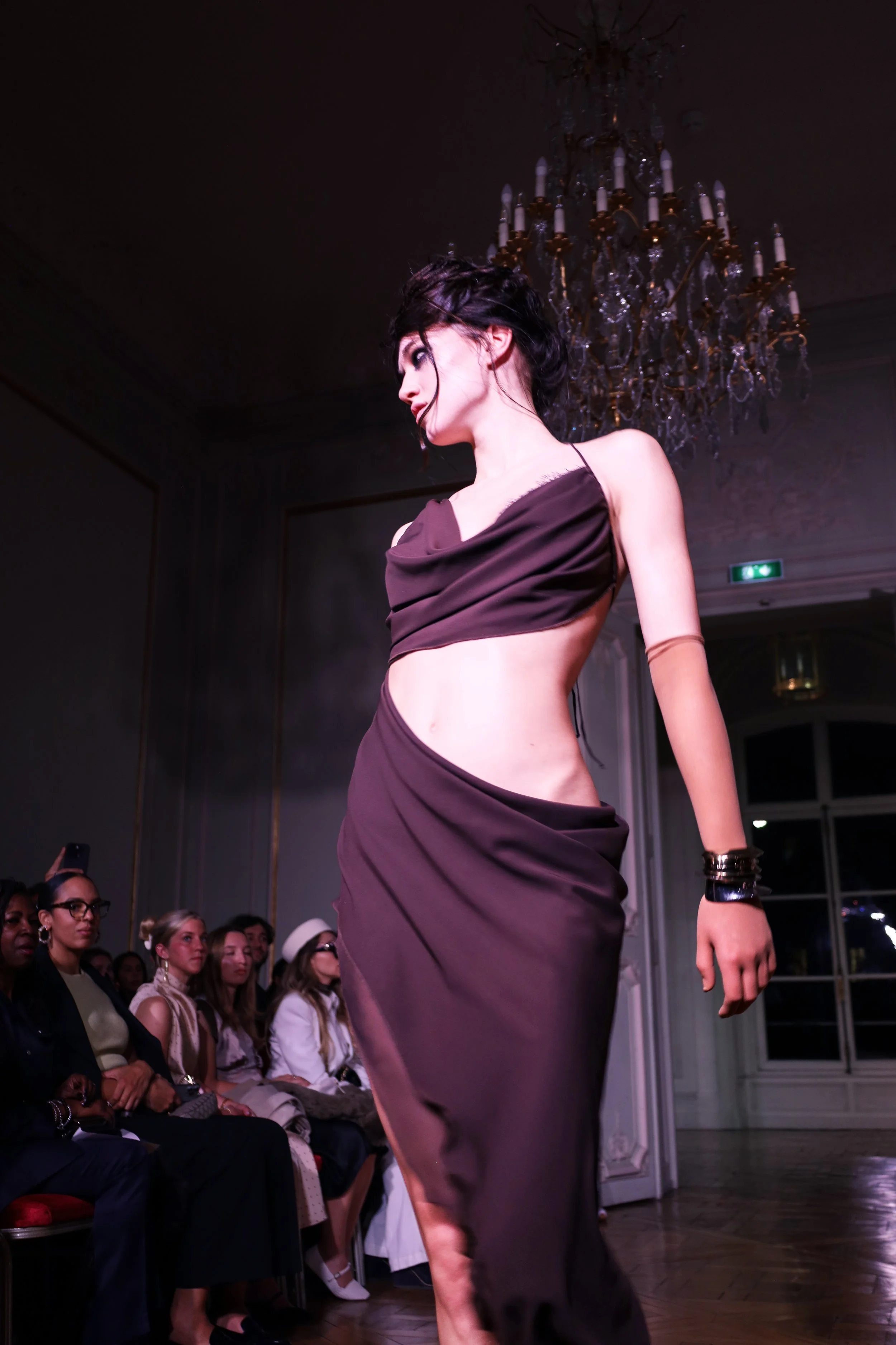 Model beneath a chandelier at a fashion presentation